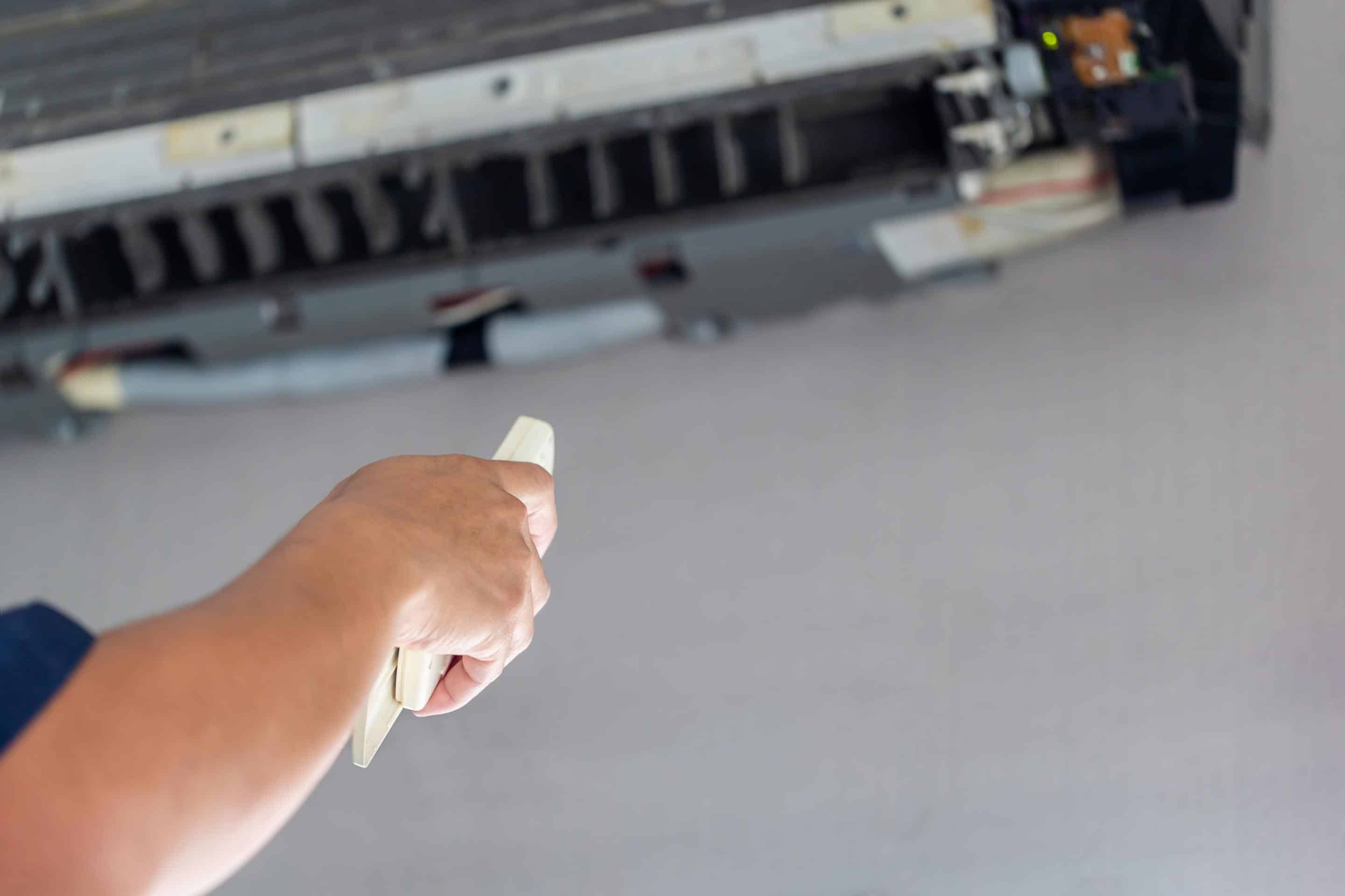 Male technician turn on air conditioner with remote control, Mal